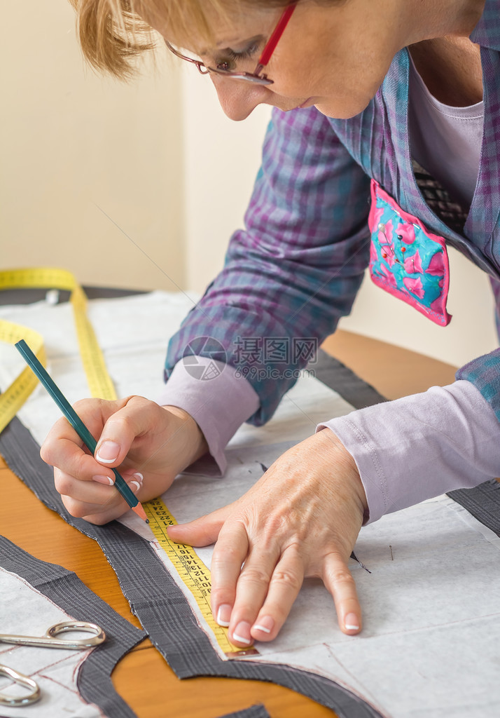 女裁缝用铅笔在桌子上画西装的裁缝图案图片