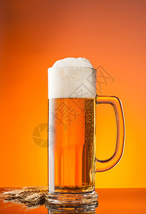 一杯带有模糊橙色背景的啤酒图片