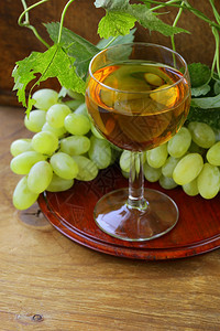 木制背景中带葡萄的白葡萄酒杯图片
