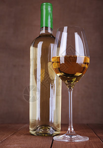 酒瓶和酒杯与木制背景上的白葡萄酒图片