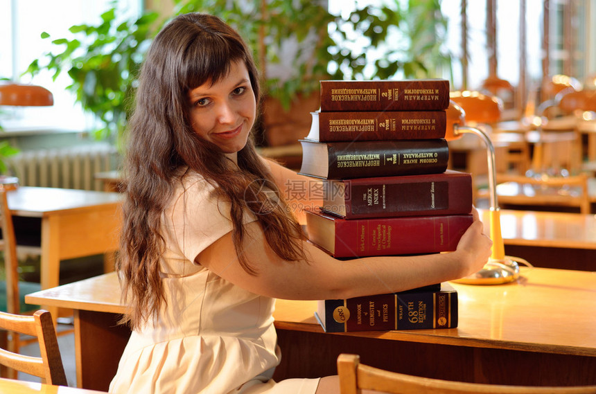 一位年轻女坐在一大批科学书籍里图片