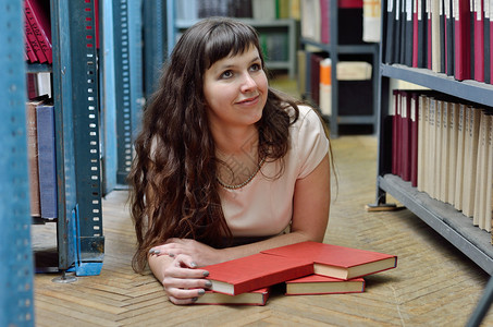 一位年轻女子躺在科学图书馆的架子之间的地板上图片