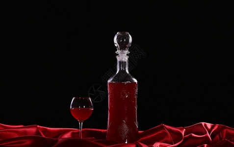 深色背景丝绸上的玻璃和酒瓶图片