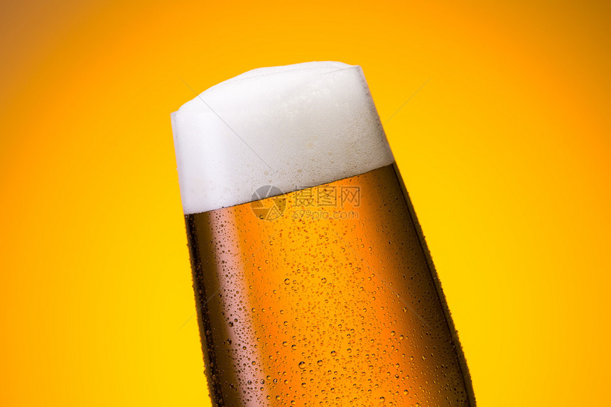 一杯含橙色背景露珠的金啤酒在演播室里拍图片
