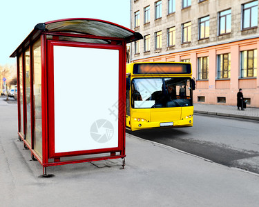街对面有空广告牌的公交车站黄色巴士靠近图片