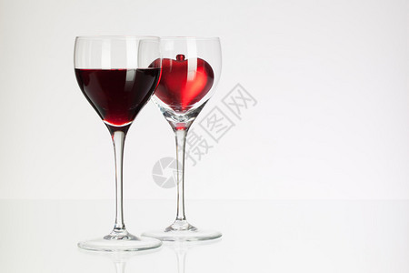 白桌上有红酒和心的酒杯图片
