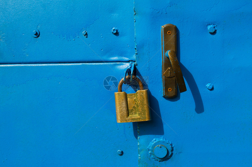 与一把旧黄铜挂锁的蓝色金属门图片