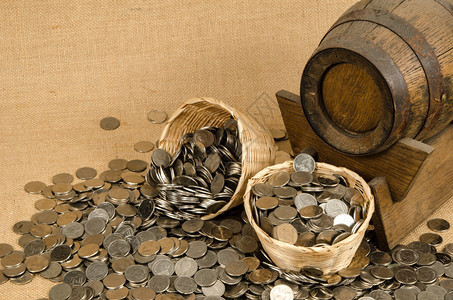 棕色麻袋背景上带木桶的一叠硬币图片