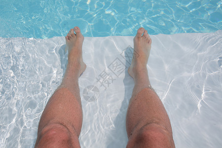 男人的脚在游泳池的背景上图片