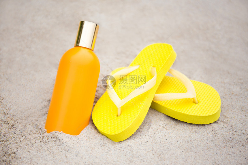 夏季和皮肤护理概念沙滩上的黄色拖图片