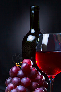 黑色背景中的红酒和葡萄图片