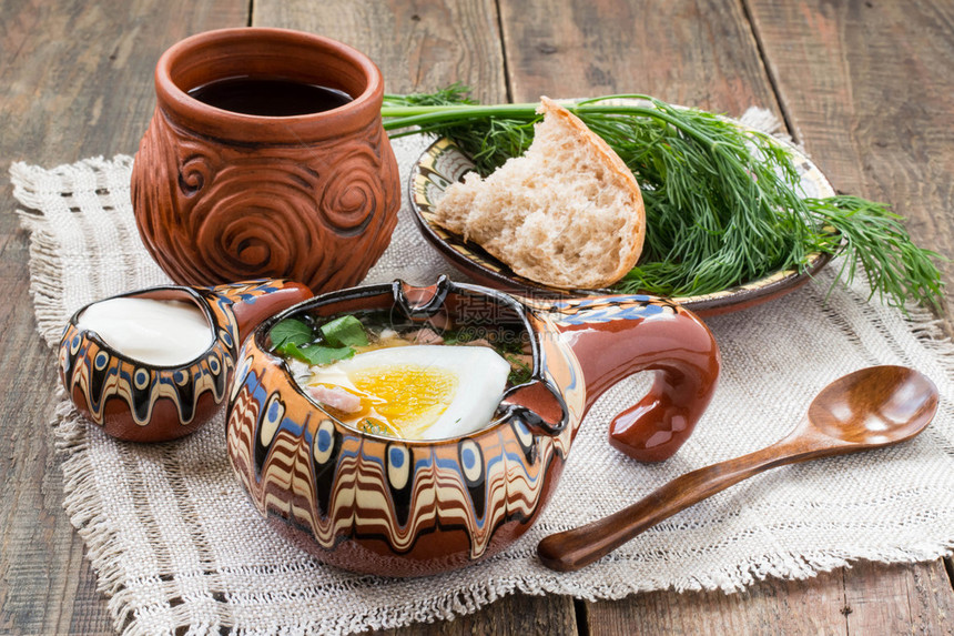 流行的俄罗斯春季冷汤okroshka与格瓦斯老式彩绘碗中的Okroshka酸奶油啤酒杯中的克瓦斯木勺面包和盘子里的莳萝图片