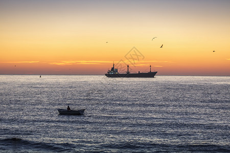美丽的日出渔民和货船在港口附近海域航行图片