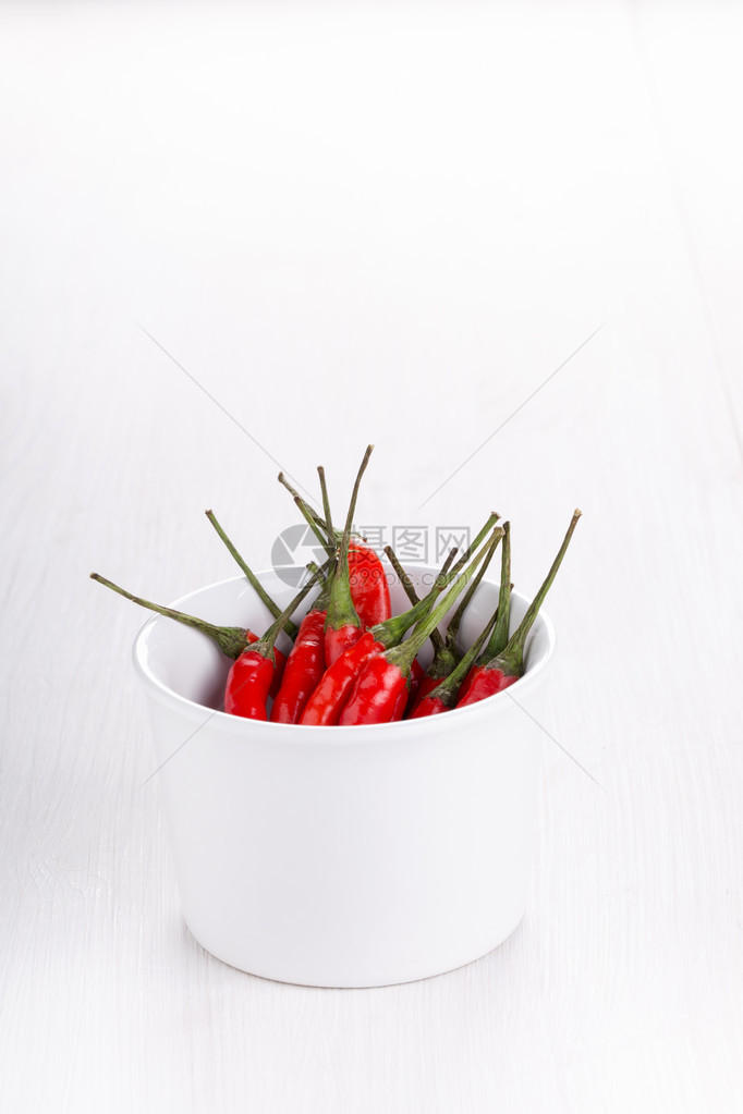 红辣椒在杯子上的红辣椒白色木制背景图片