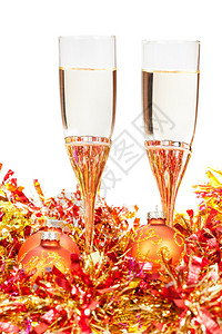 在黄色和金黄色的圣诞装饰品上两杯闪亮的葡萄酒孤图片