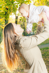 美丽的母亲带着她的宝贝女儿在秋天的公园户外幸福家庭的概念孩子坐在她图片