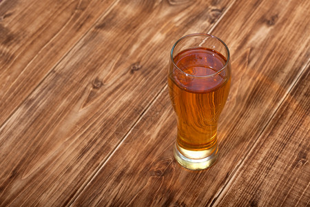 一杯淡啤酒靠近木质背景棕色背景图片