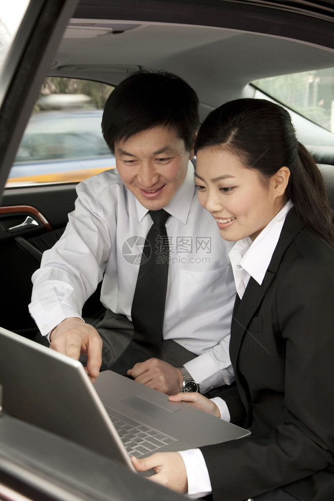 在汽车后座使用笔记本电脑工作的商人图片