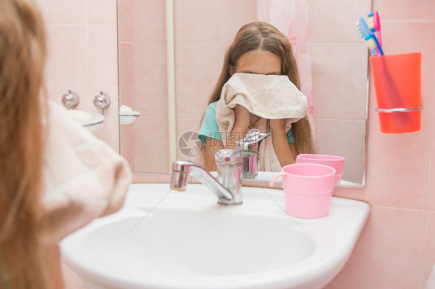 六岁的女孩用毛巾擦脸在浴室的图片