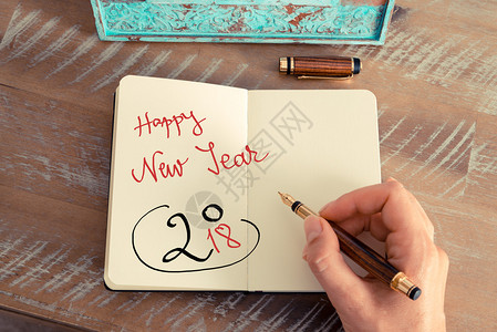 复古效果和女人手在笔记本上用钢笔写便条的色调图像励志概念与手写文本新年快背景图片