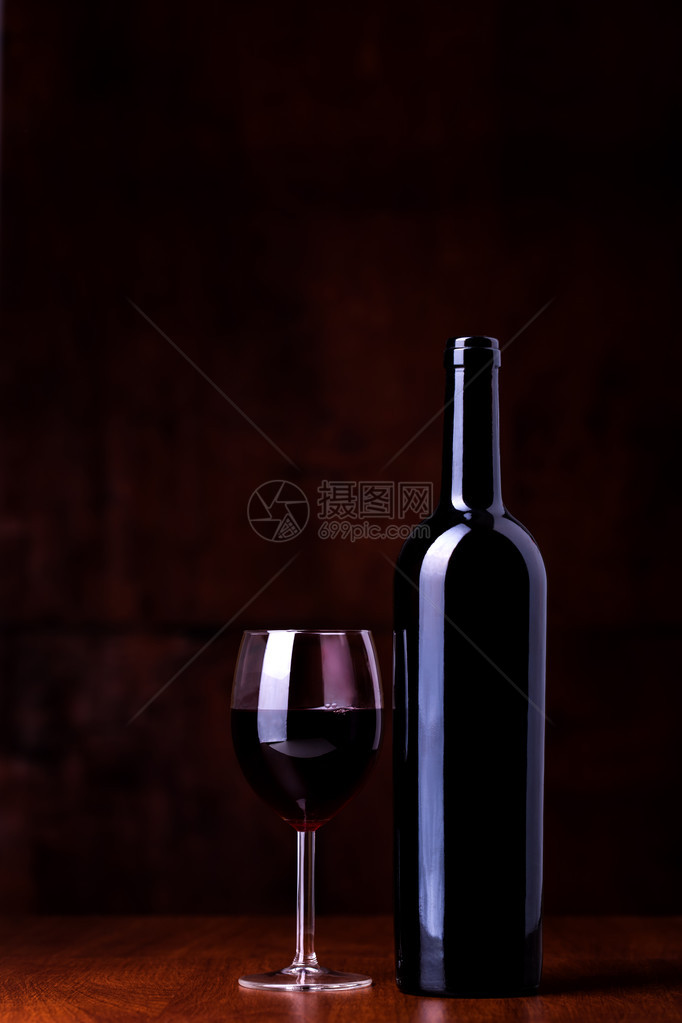 深色背景中的一瓶红酒和一杯图片