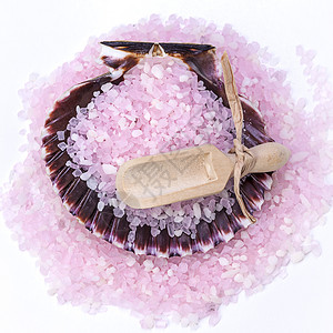 粉红色的浴盐和贝壳内的木勺图片