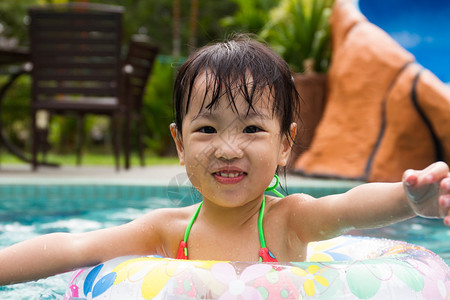 亚洲小女孩在游泳池里玩游泳圈图片