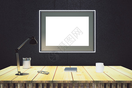 黑墙上一幅空白的画框用木桌和灯图片