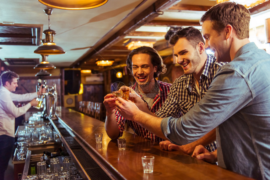 三个身穿休闲服的年轻人坐在酒吧的台边图片
