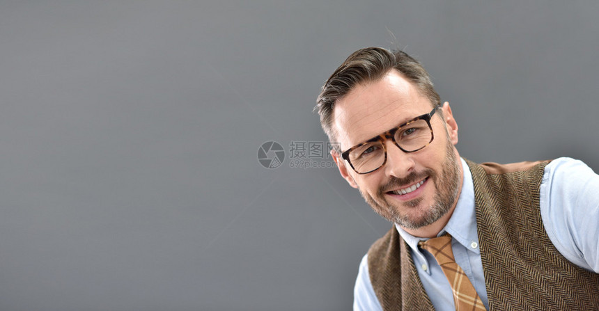 站在灰色背景上戴眼镜的成熟男人图片