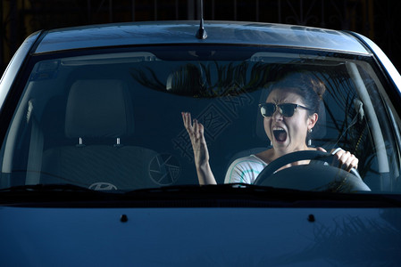 驾驶者愤怒的女人在开车时对背景