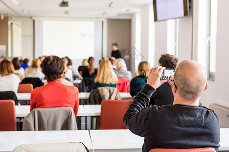 商业会议的观众用智能手机拍照的观众图片