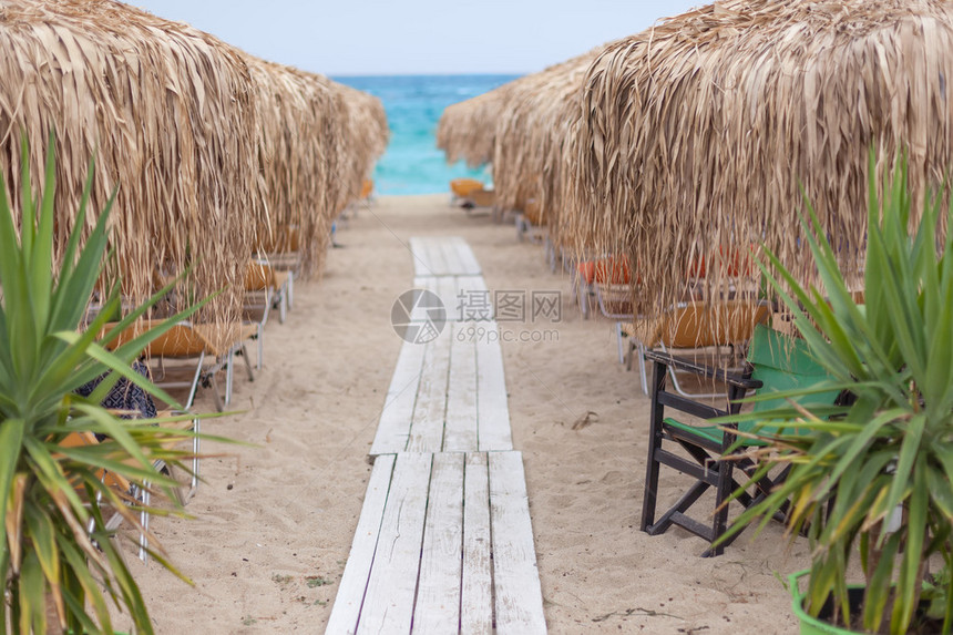 早上通过沙滩椅和茅草伞在美丽的海滩上通往大海的小路浅景深爱琴图片