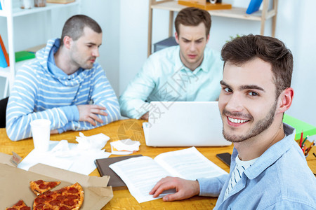 年轻编程员用披萨拿笔记本电脑工作图片