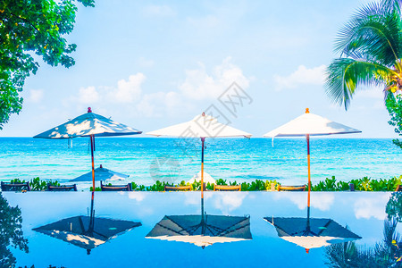 酒店度假村海滩和大海附近的游泳池周围美丽的豪华雨伞池和椅子图片