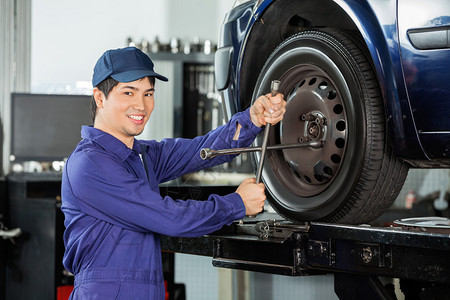 在停车场修理汽车轮胎的男机械修车机工充图片