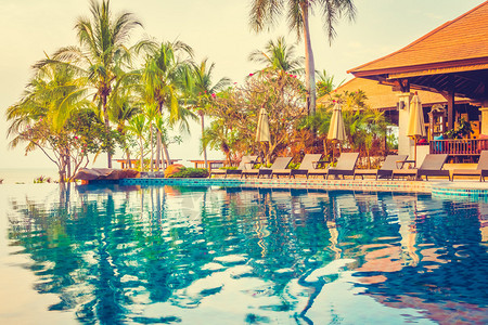 酒店泳池度假村中棕榈树和大海背景的美丽豪华游泳池图片