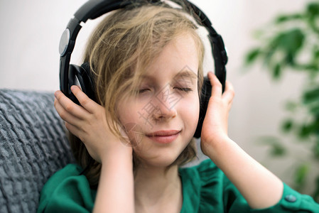 小女孩在耳机里听音乐图片