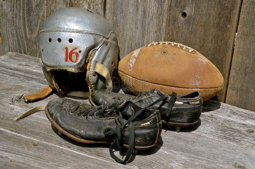 旧的皮革橄榄球鞋子和头盔图片
