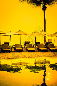美丽的剪影豪华伞和椅子在酒店泳池度假村的游泳池周围图片