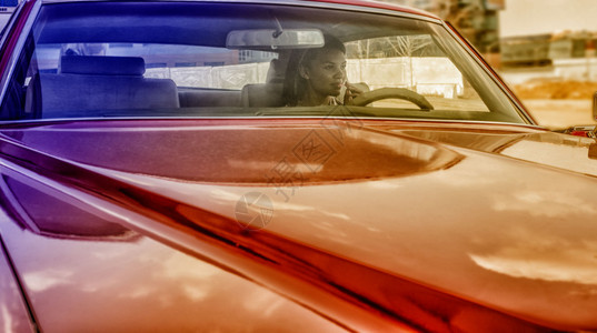 坐在红色复古老爷车内的年轻成年美丽非洲裔美国女肖像非洲女孩手拿一图片