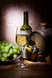 酒瓶小桶子一堆葡萄和白酒杯放在图片