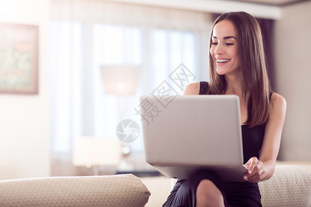活生的年轻美女坐在并使用笔记本电脑时图片
