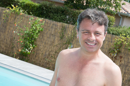 一个英俊和快乐的中年男人在游泳池里放松笑着带完美的牙齿微笑图片