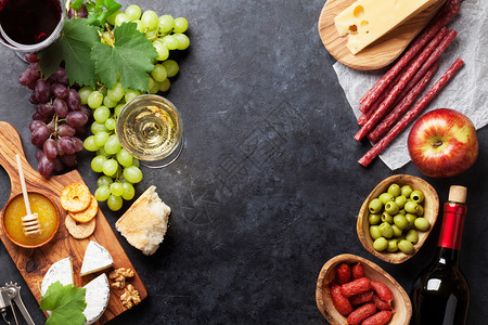 石桌上的红白葡萄酒葡萄奶酪和香肠带复制空间的顶视图图片