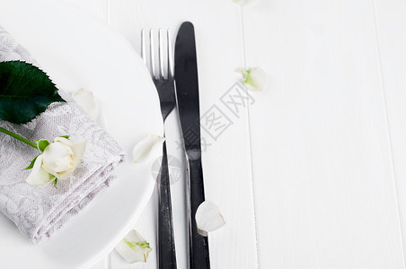 白色背景上带餐巾和玫瑰的盘子图片