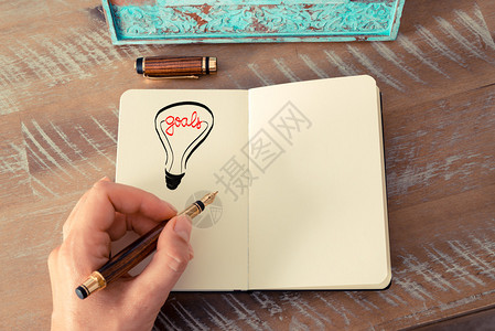 一个女人用钢笔在记本上画一个灯泡的复古效果和色调图像图片