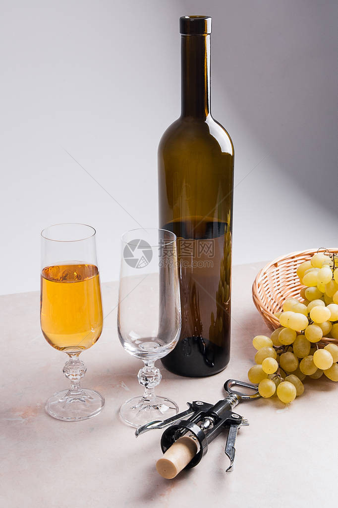 一个是白葡萄酒棕色瓶酒和浅色大理石背景上的开瓶器图片