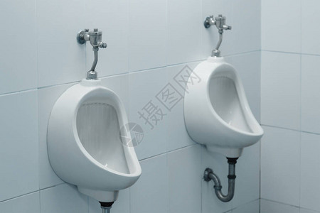 男厕所里的白色小便池背景图片