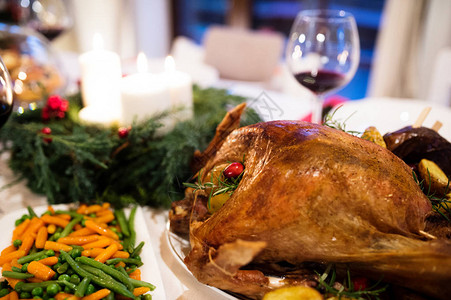 圣诞大餐摆在装饰餐厅的桌子上烤火鸡或肉蔬菜圣诞花图片